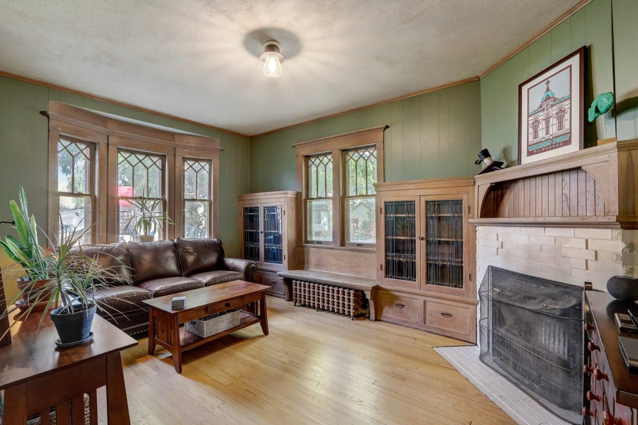 Living room with original woodwork, built-in cabinetry, and a brick fireplace